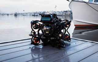 SRV-8 ROV sitting on a dock with a large boat in the water behind it