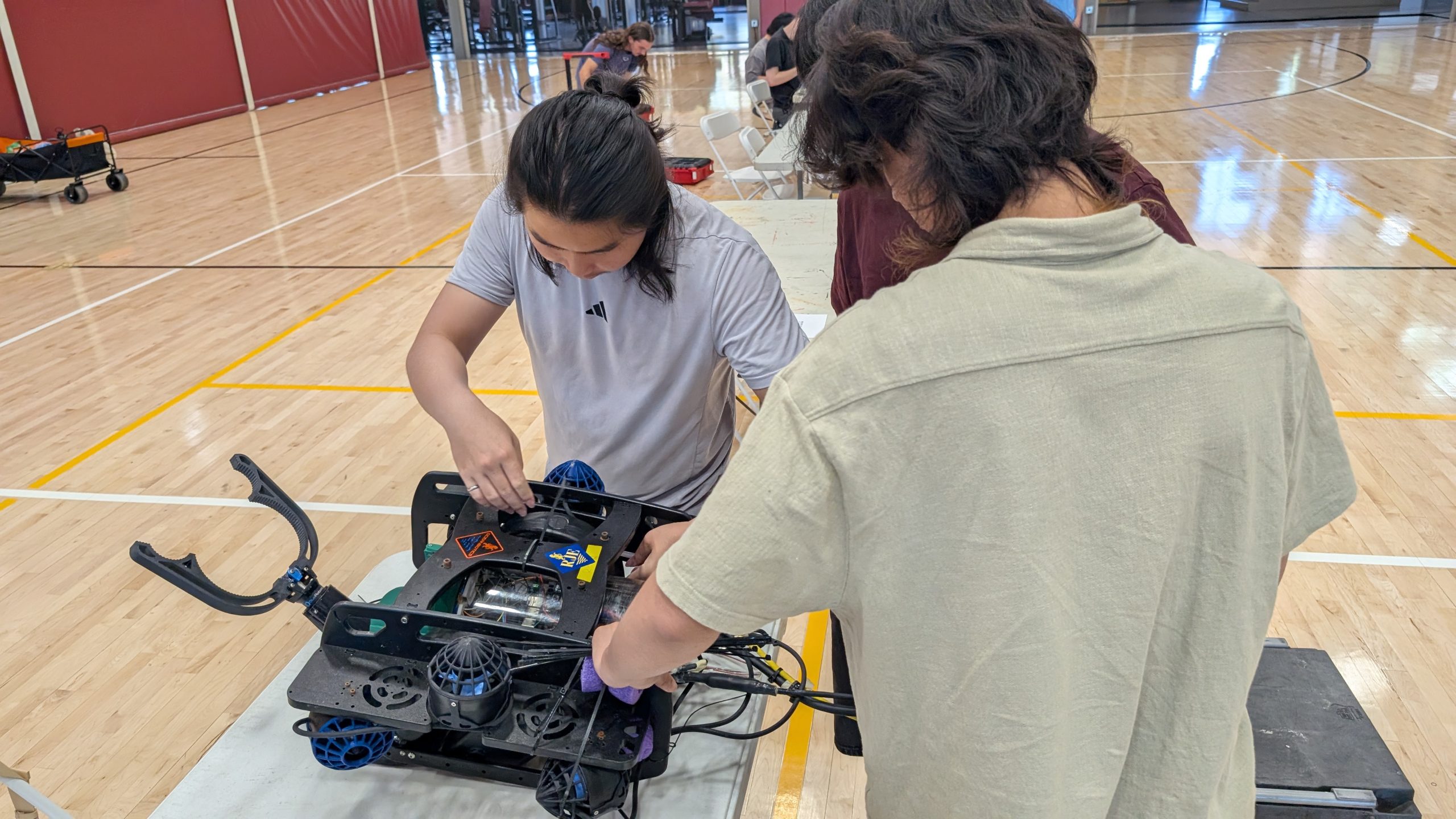 CSUF Titan ROV team working on their remotely operated vehicle, fir with an Oceanbotics sticker. 